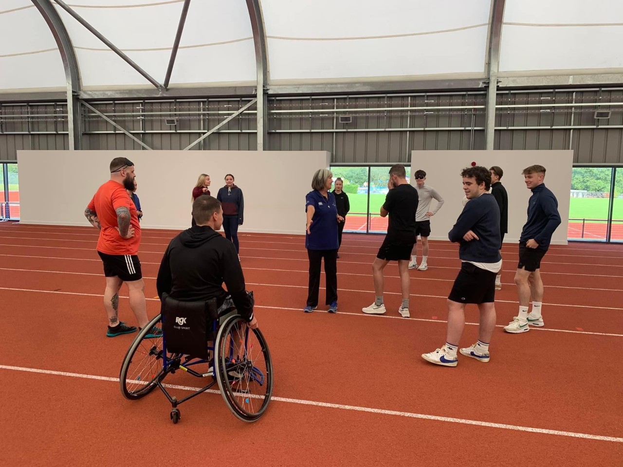 group of students on an indoor athletics track receiving disability inclusion training
